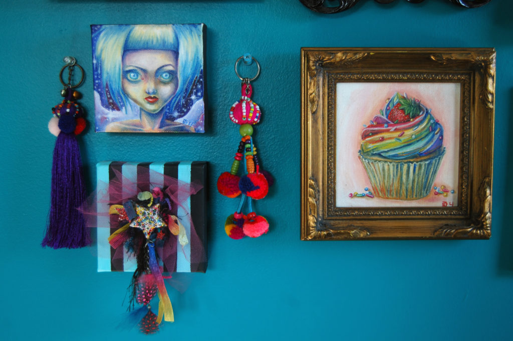 Close-up of colorful paintings and wall decorations on a teal wall.
