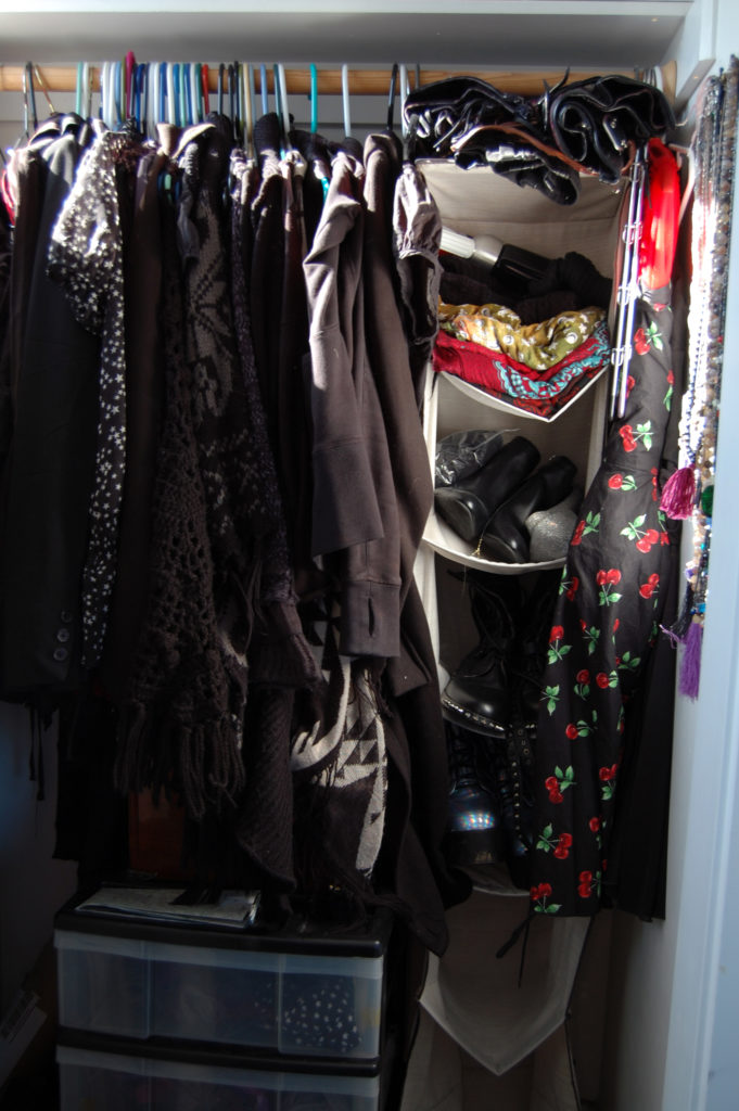 An organized closet filled mostly with black clothes