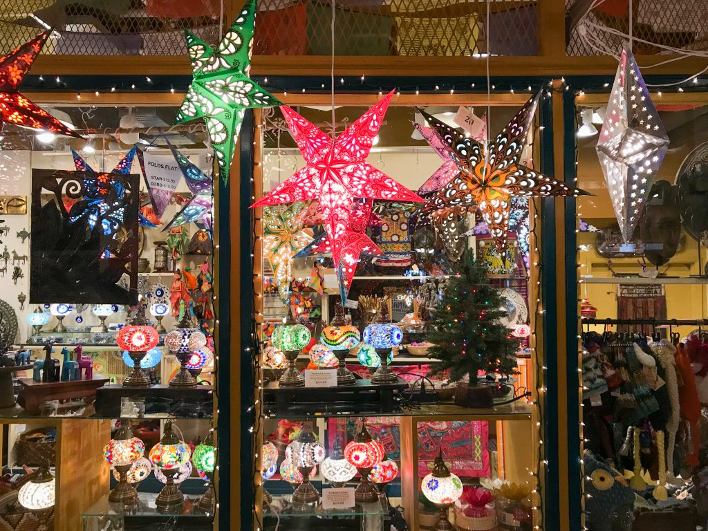A glowing storefront window featuring hanging star lamps and Turkish glass lamps.