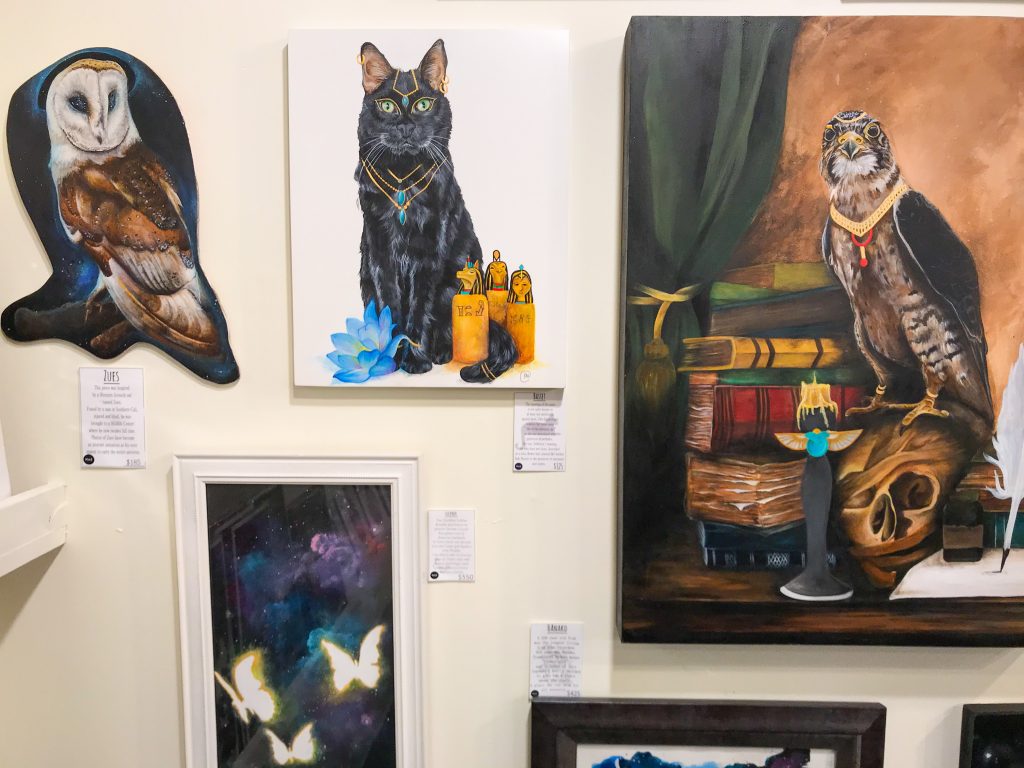 Fantasy-themed paintings of animals are displayed on a wall.