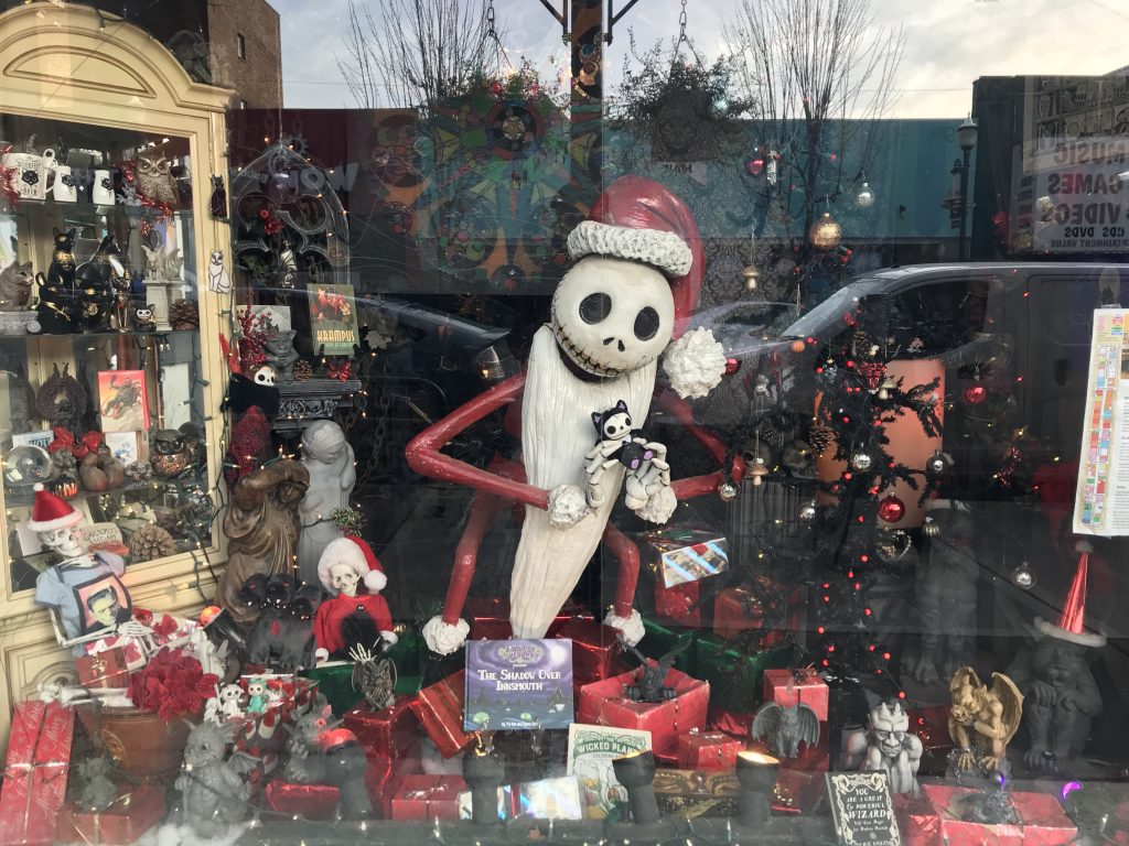 A storefront window featuring Jack Skellington of Nightmare Before Christmas, surrounded by red and black gift boxes and holiday ornaments.