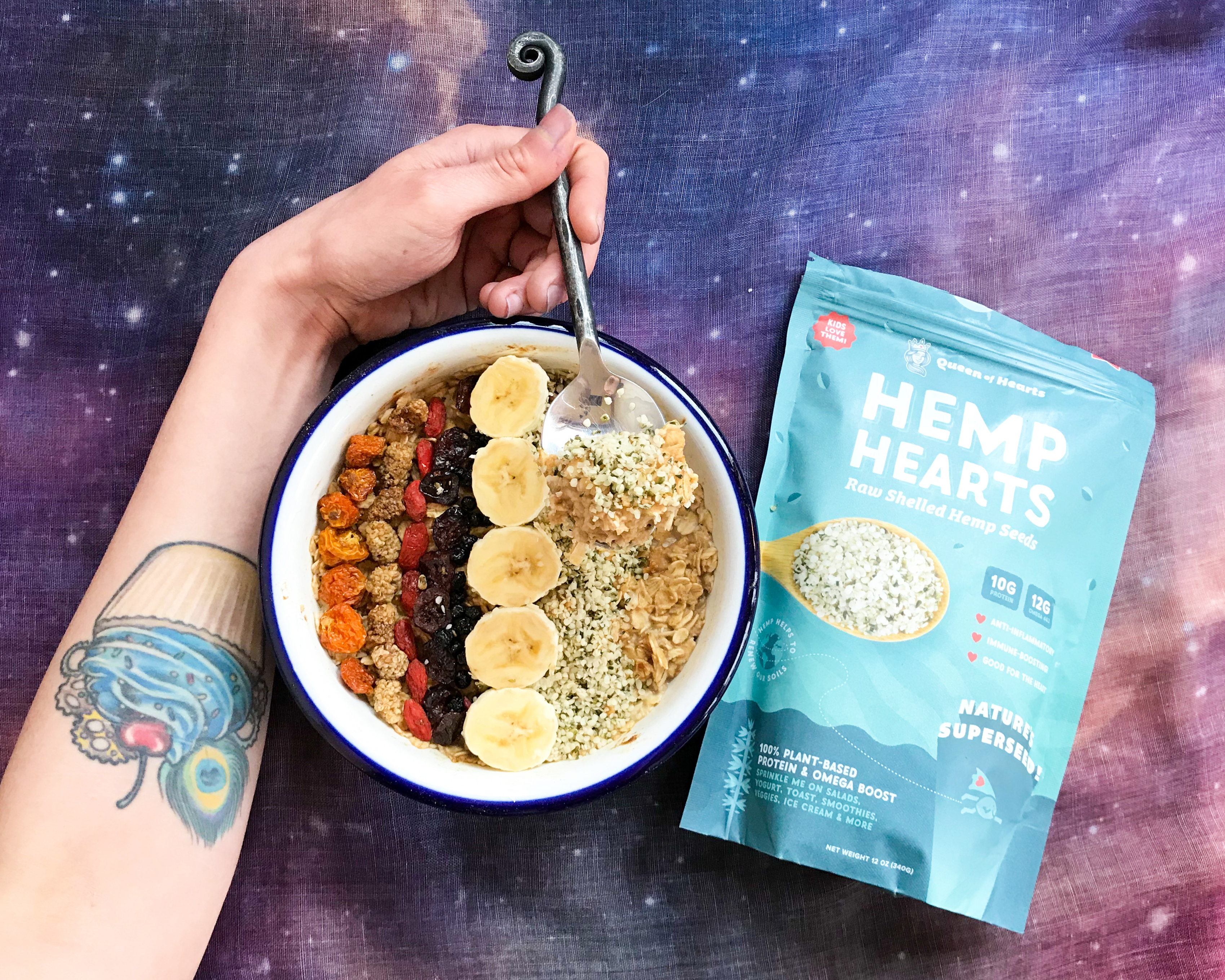 An arm spooning oatmeal with hemp seeds out of a bowl, next to a bag of hemp hearts