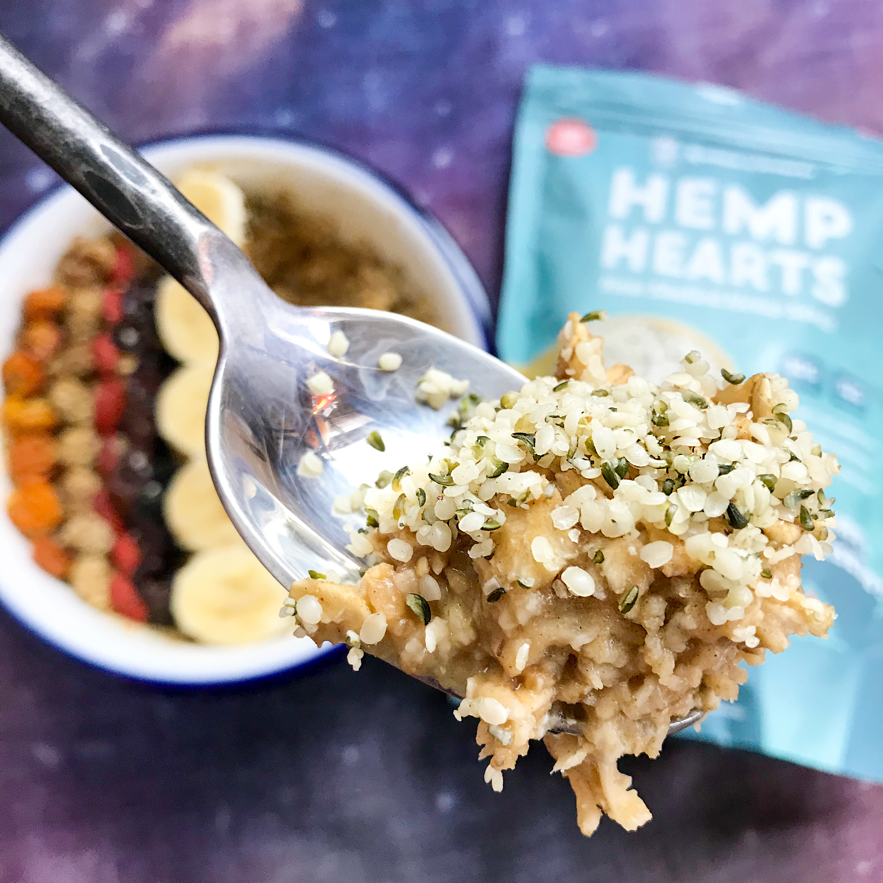 Oatmeal and hemp hearts in the spoon, with the bowl and hemp hearts package in the background.