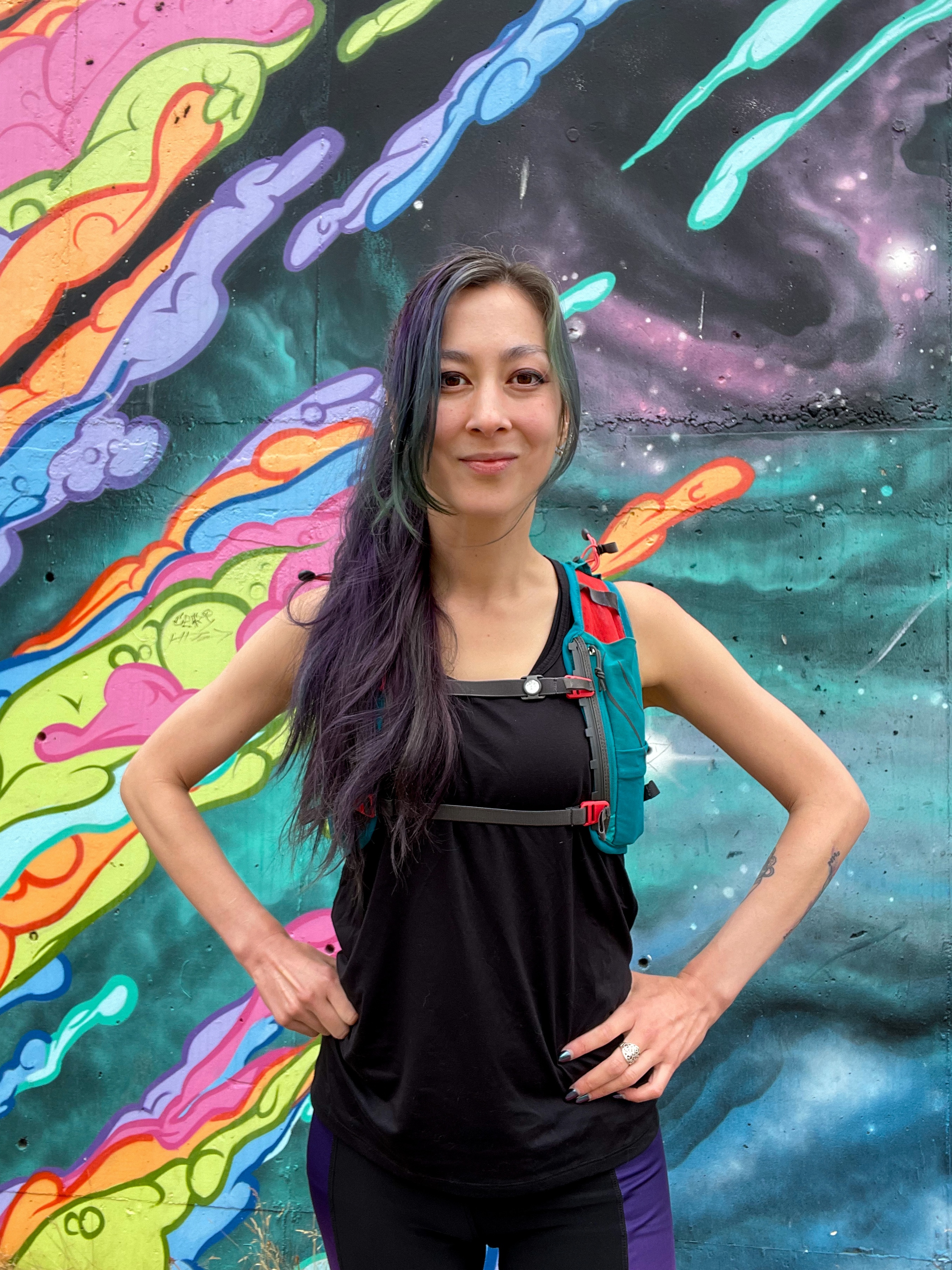 Ronnie stands with hands on her hips in front of an outer space background.