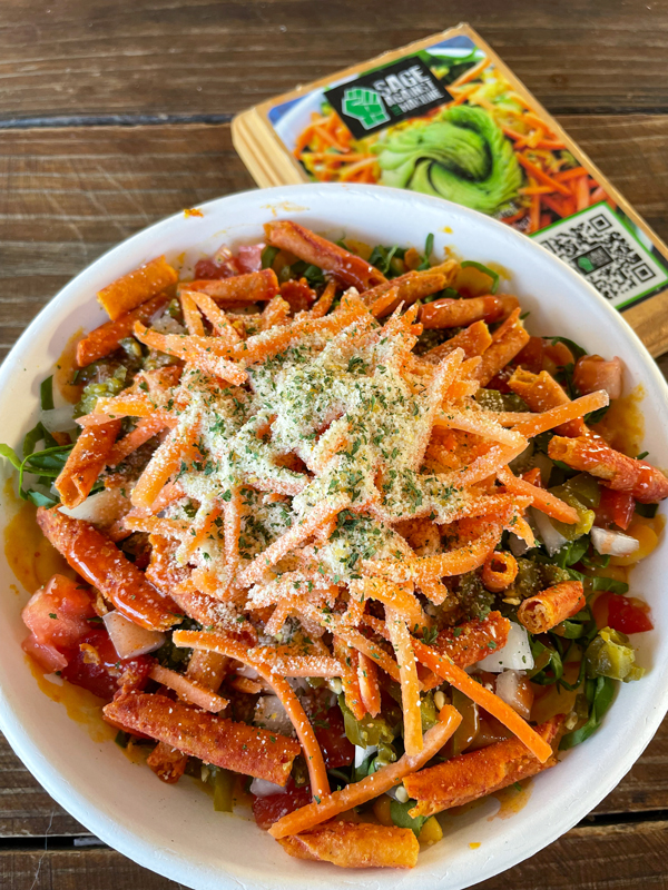 The Spicy Mac has shredded carrots, tomatoes, pickled jalepenos, and macaroni noodles on top of a bed of greens.