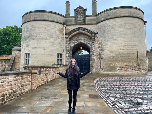 Ronnie stands in front of the arched stone gate of Nottingham Castle