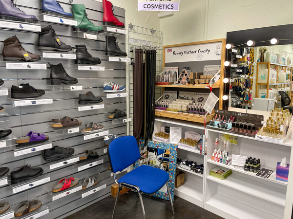 In one corner of V-Spot, a wall rack of leather-free boots, sneakers, and sandals is next to a display stand offering many vegan cosmetics.