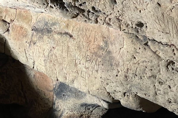 Repeating letters and symbols are carved into the limestone.
