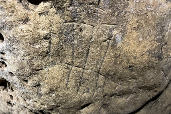 A carved witch mark ambiguously depicts the number 777 or 1777.